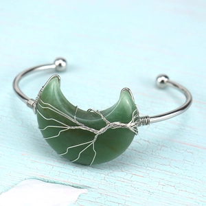 Macro shot of silver wire-wrapped tree of life on green crescent stone moon bracelet