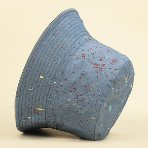 Détail d'un chapeau bob en coton bleu avec graffitis et taches de peinture colorées