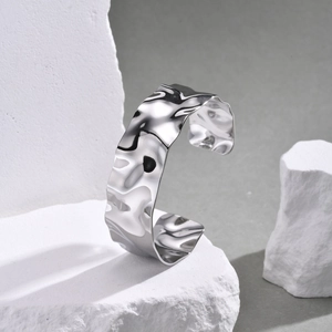 Close-up of silver stainless steel cuff bracelet with irregular wavy texture detail