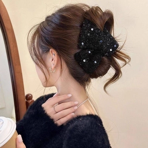Détail de la pince à cheveux élégante en tweed noir avec paillettes argentées sur cheveux