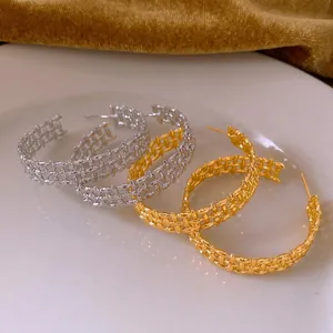 Luxurious gold and silver plated C-shaped earrings with woven mesh texture on white plate