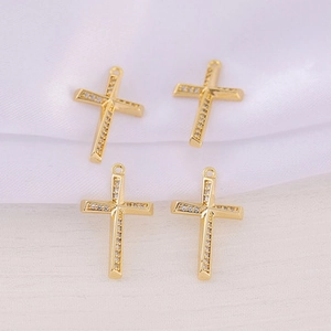 Detailed close-up of four golden cross pendants with zircon inlay on white silk