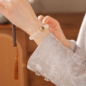 Detailed view of clear crystal bead bracelet with a polished gold focal bead on wrist