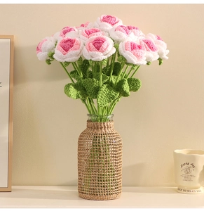 Detail of hand-crocheted roses in pink and white inside a rattan-wrapped glass vase