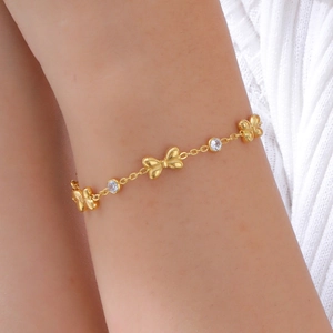 Gros plan d'un bracelet doré avec nœuds et zircons porté sur un poignet délicat