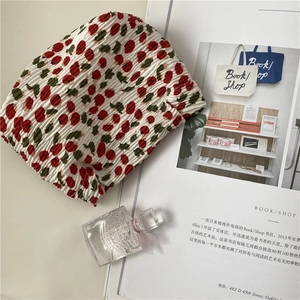 Detail of smocked fabric pouch with cherry print next to a glass perfume bottle