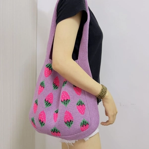 Close-up of purple knitted tote bag featuring pink and green strawberry patterns