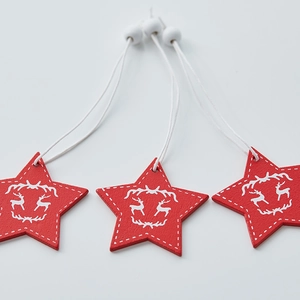 Three red wooden star ornaments with white reindeer prints for Nordic Christmas decor