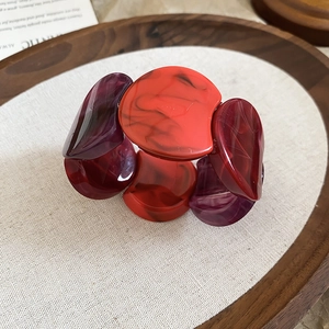 Detailed close-up of amber and purple acrylic segments with marble texture on wide bangle