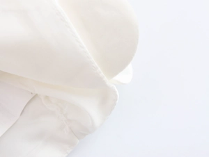Close-up of premium white fabric texture and fine stitching detail on a crop top