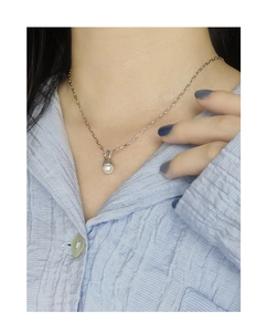 Close-up of S925 silver necklace featuring a black onyx and white pearl pendant on a neck