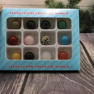 Detailed view of 12 natural polished stone spheres in a blue striped gift box set