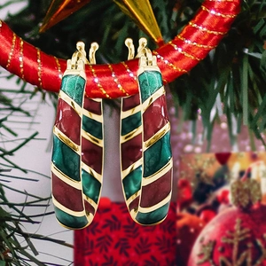 Close-up of red and green enamel C-shaped Christmas hoop earrings with gold stripes