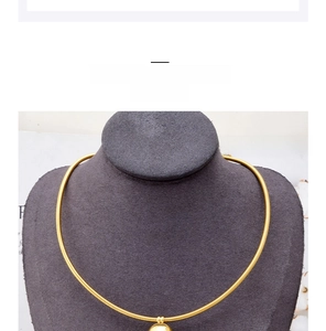 Detail of a minimalist gold snake chain necklace with a sleek round pendant on a model