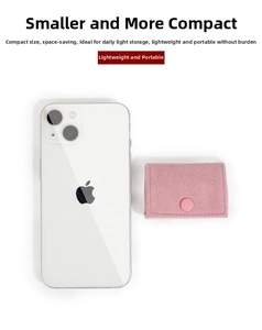 Roze suède sieradenzakje naast een telefoon om het compacte formaat te demonstreren