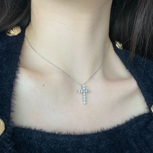 Close-up of S925 sterling silver cross necklace with zircons on a female model