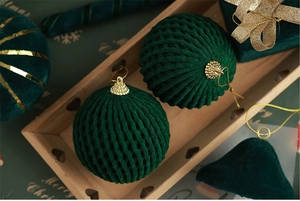 Close-up of luxury dark green velvet Christmas balls with ribbed texture and gold caps