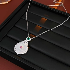 Detailed macro view of jade pendant with zircon stones on a black jewelry tray