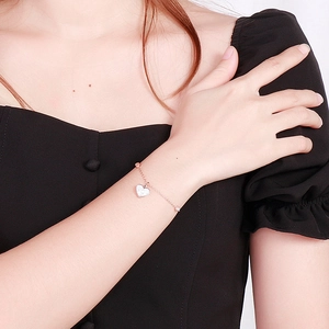 Dettaglio del bracciale a cuore in oro rosa con strass indossato da un polso femminile