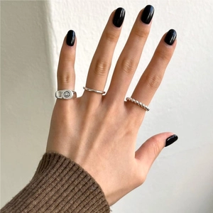 Close-up of minimalist silver rings set featuring smiley face and beaded bands on a model