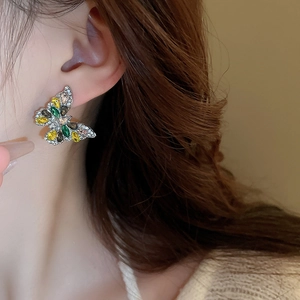 Close-up of sparkling butterfly drop earrings with emerald and yellow pear-cut crystals