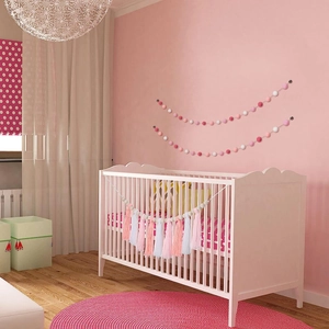 Detailed view of pink and white pom pom garland and tassel hanging in a baby nursery