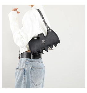 Close-up of a black bat-shaped PU leather crossbody bag with chain and skull detail