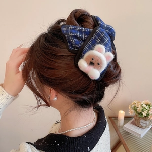 Detailed view of blue tweed bow hair claw with a cute plush bear on a model's hair