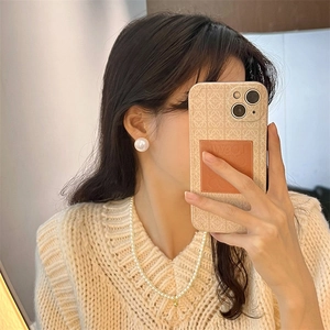 Elegant pearl studs and necklace worn with a warm beige cable knit sweater in soft light