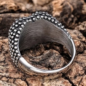 Close-up of industrial style stainless steel ring with textured dots and brushed metal finish
