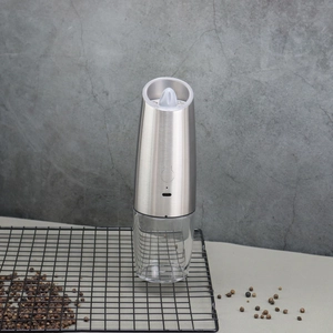 Close-up of electric pepper grinder on black metal rack with peppercorns for cooking