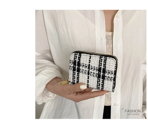 Close-up of black and white tweed mini coin purse with gold zipper and stylish metal puller
