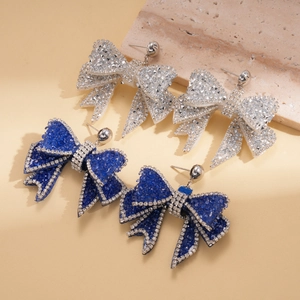Close-up of luxury bow earrings with sparkling rhinestones in silver and royal blue colors