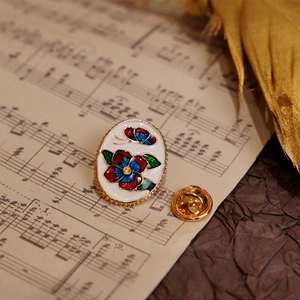Floral enamel brooch with butterfly design and gold trim on vintage sheet music