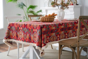 Close-up of red ethnic jacquard tablecloth featuring colorful geometric patterns and white tassels