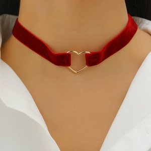 Close-up of deep red velvet choker featuring a polished gold heart pendant on model