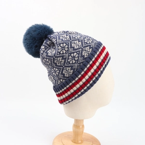 Winter knitted beanie with navy Nordic patterns and a large faux fur pompom on top