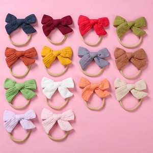Flat lay of 14 colorful cotton muslin baby bow headbands in various vibrant shades