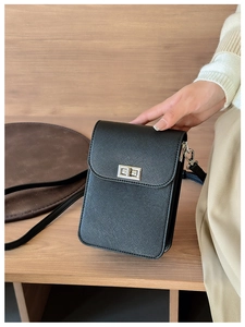 Detail of black mini crossbody bag featuring crossgrain texture and silver twist lock closure
