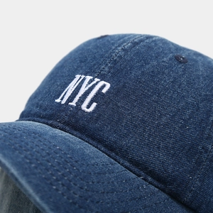Detailed close-up of white NYC embroidery and premium denim texture on a baseball cap