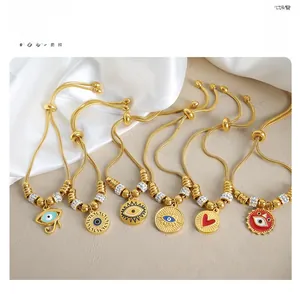 Detail of 18k gold plated bracelets with evil eye charms and heart on silk background