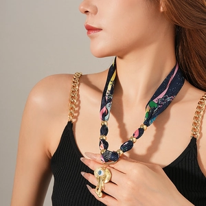 Dettaglio della collana foulard in seta boho con ciondolo a elefante dorato e occhio blu