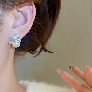 Macro shot of an elegant pearl and zircon cluster stud earring worn by a model