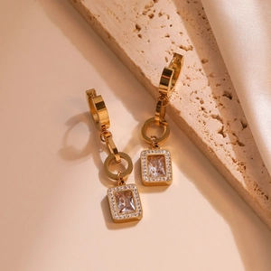 Elegant gold titanium steel geometric earrings with sparkling zircon on stone background