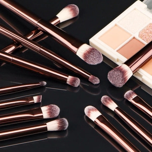 Detailed view of 13 professional makeup brushes with copper handles and dual-tone bristles