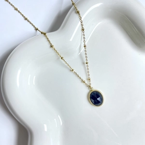 Detail of bohemian deep blue oval gemstone pendant on a golden satellite chain
