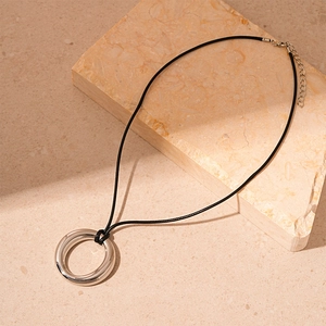 Close-up of minimalist silver metal ring pendant on black cord with lobster clasp
