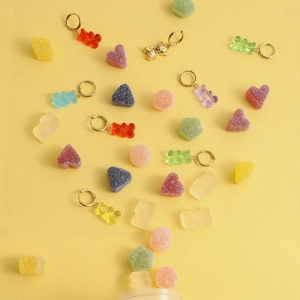 Boucles d'oreilles oursons colorés en résine avec anneaux dorés sur fond jaune
