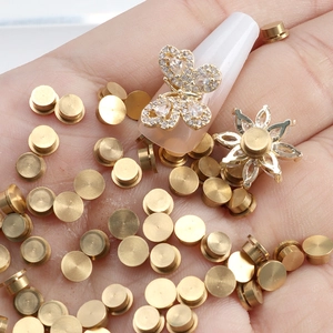 Accesorios dorados para uñas con lazo de diamantes y dijes de flores en la mano