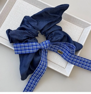 Close-up of a dark blue checkered bow scrunchie on a light textured background